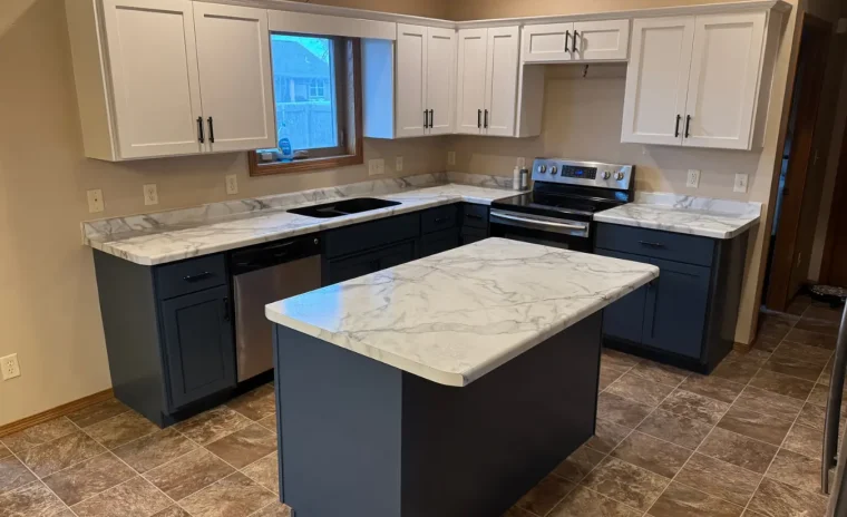 A newly remodeled kitchen features white upper cabinets, dark blue lower cabinets, and a matching island.