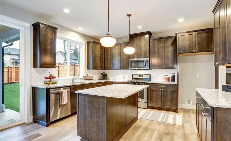 [USED] Modern kitchen with dark wood cabinets, granite countertops, and stainless steel appliances. A central island stands under two hanging pendant lights.