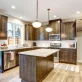 [USED] Modern kitchen with dark wood cabinets, granite countertops, and stainless steel appliances. A central island stands under two hanging pendant lights.